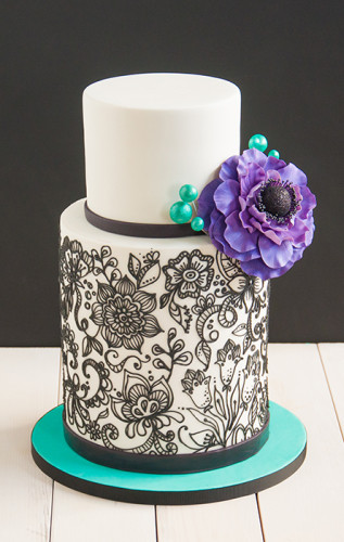 Black pipping on white birthday cake with big purple flower