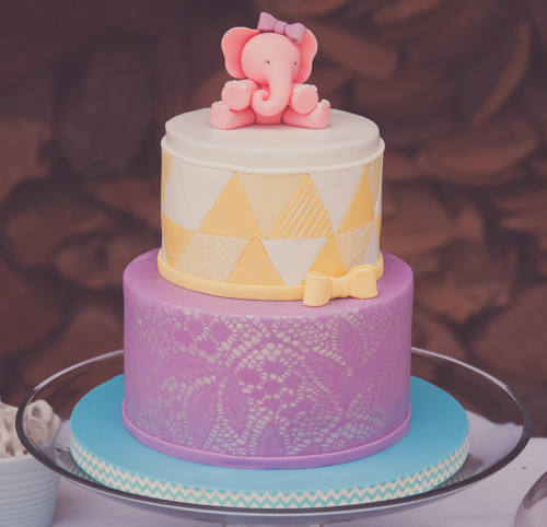 Pink elephant with bow on top of yellow and purple baby shower cake. Lace airbrush and quilting technique.